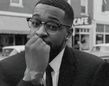 a man in a suit and tie is sitting in front of a cafe sign