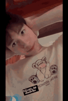 a young man is wearing a t-shirt with a teddy bear on it and a sticker that says first xp