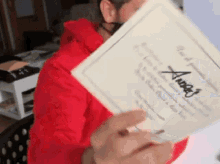 a man in a red hoodie is holding a piece of paper with the name angel written on it