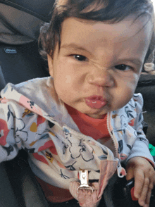 a baby is making a funny face in a chicco car seat