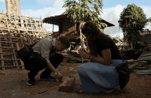 a man and a woman kneeling down in front of a wooden structure