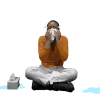 a woman is sitting on the floor with her legs crossed and a box of tissues in front of her