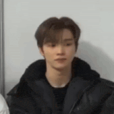 a close up of a young man wearing a black jacket and a black shirt .