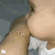 a baby is kissing a woman 's arm while wearing a bracelet on her wrist .
