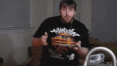 a man wearing a black evangelion shirt holds a plate of food