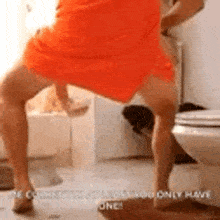 a woman in an orange dress is standing next to a toilet .