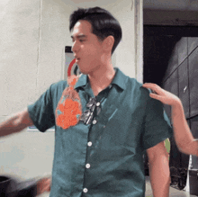 a man in a green shirt with a tie on his neck is being held by a woman