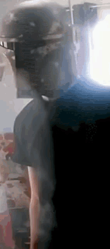 a person wearing a helmet and sunglasses is standing in front of a window .