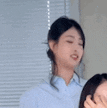 a woman in a blue shirt is making a funny face and looking at the camera .