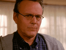 a man wearing glasses and a plaid shirt is looking at the camera