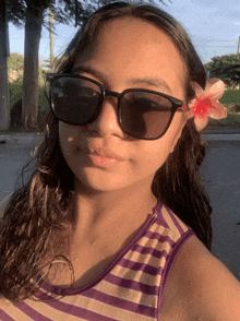 a young girl wearing sunglasses and a flower in her hair