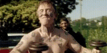 a man with tattoos on his chest is lifting a dumbbell .