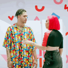 a woman with red hair is talking to a man with dreadlocks