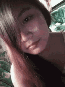 a woman with long hair is taking a selfie while laying on a couch .