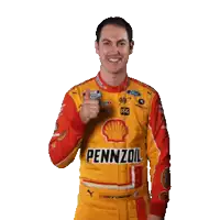 a man in a pennzoil shirt gives a thumbs up sign