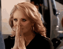 a woman with a ring on her finger holds her hands together in prayer