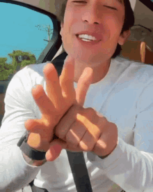a man wearing a white shirt and a black watch is sitting in a car