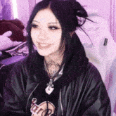 a girl wearing a hard rock shirt and a black leather jacket smiles
