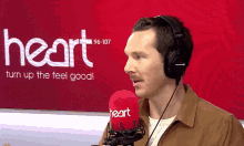 a man wearing headphones holds a microphone in front of a heart 96-107 sign