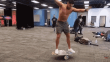 a shirtless man balances on a balance board in a room