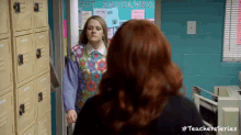 two women are standing next to each other in a room with lockers .
