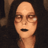 a close up of a woman wearing glasses and black makeup