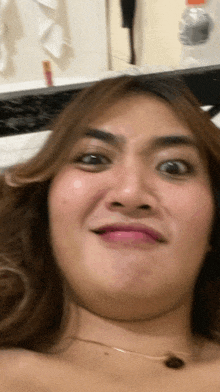 a woman making a funny face with a bottle of water behind her