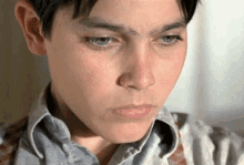 a close up of a young boy 's face with a sad look on his face