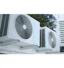 two air conditioners are mounted to the side of a building .