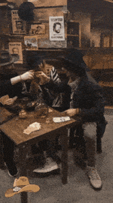 a group of people sitting around a table with wanted posters on the wall behind them