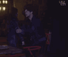a man and woman hugging in a dark room with the words lulu gifs on the bottom right