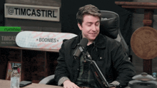 a man sitting in front of a microphone with a sign that says timcastirl on it