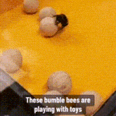 these bumble bees are playing with toys on a yellow table .