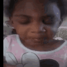 a little girl is making a funny face with her eyes closed and a mickey mouse shirt on .