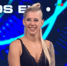 a woman with a tattoo on her arm is smiling in front of a blue background that says os e