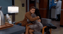 a man is hugging a woman while sitting in a chair in a hospital
