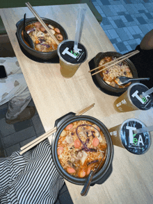 two bowls of food and two cups of tea sit on a wooden table