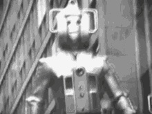a black and white photo of a robot standing on a city street .