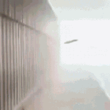 a blurred image of a person walking down a hallway with a white wall .