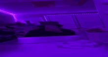 a person is taking a selfie with their phone in a room with purple lights .