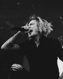 a man with curly hair is singing into a microphone in a black and white photo