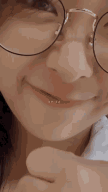 a close up of a girl wearing glasses and giving a thumbs up sign