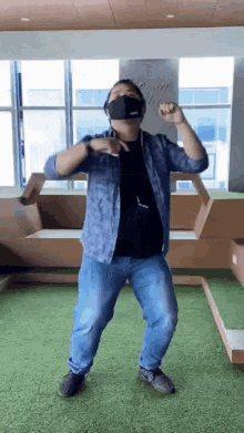 a man wearing a mask is dancing in a room with a lot of windows .