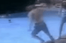 a man is walking underwater in a swimming pool while a woman watches .