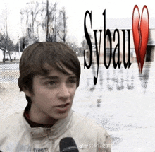 a young boy talking into a microphone with sybau written on the background