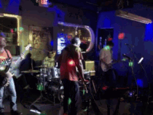 a group of people playing instruments in a dark room with an exit sign in the background