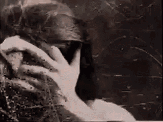 a black and white photo of a person talking on a cell phone in a dark room .