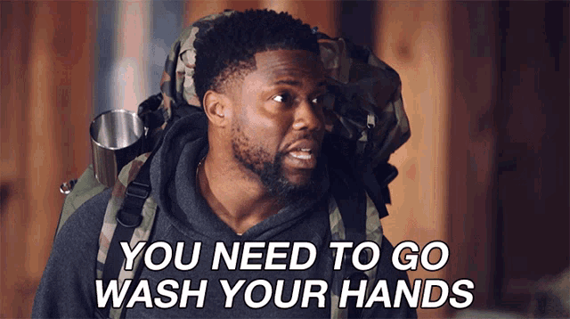 a man carrying a backpack with the words you need to go wash your hands above him