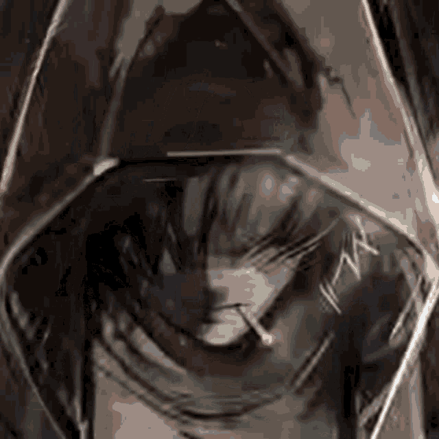 a close up of a person wearing a hooded jacket smoking a cigarette .