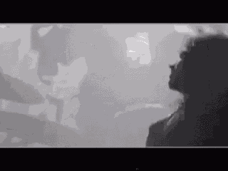 a black and white photo of a woman standing in front of a crowd .